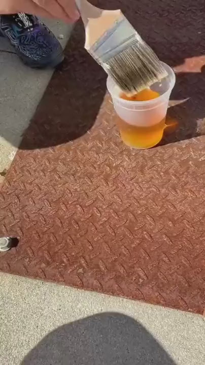 Applying Kompozit plant-based Rust Converter with a brush on a rusted steel plate