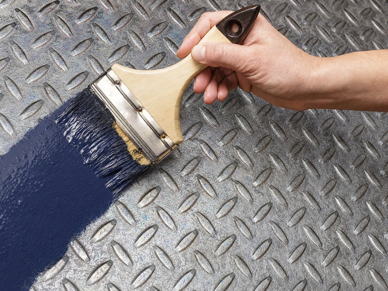 Brushing dark blue paint over the treated steel plate